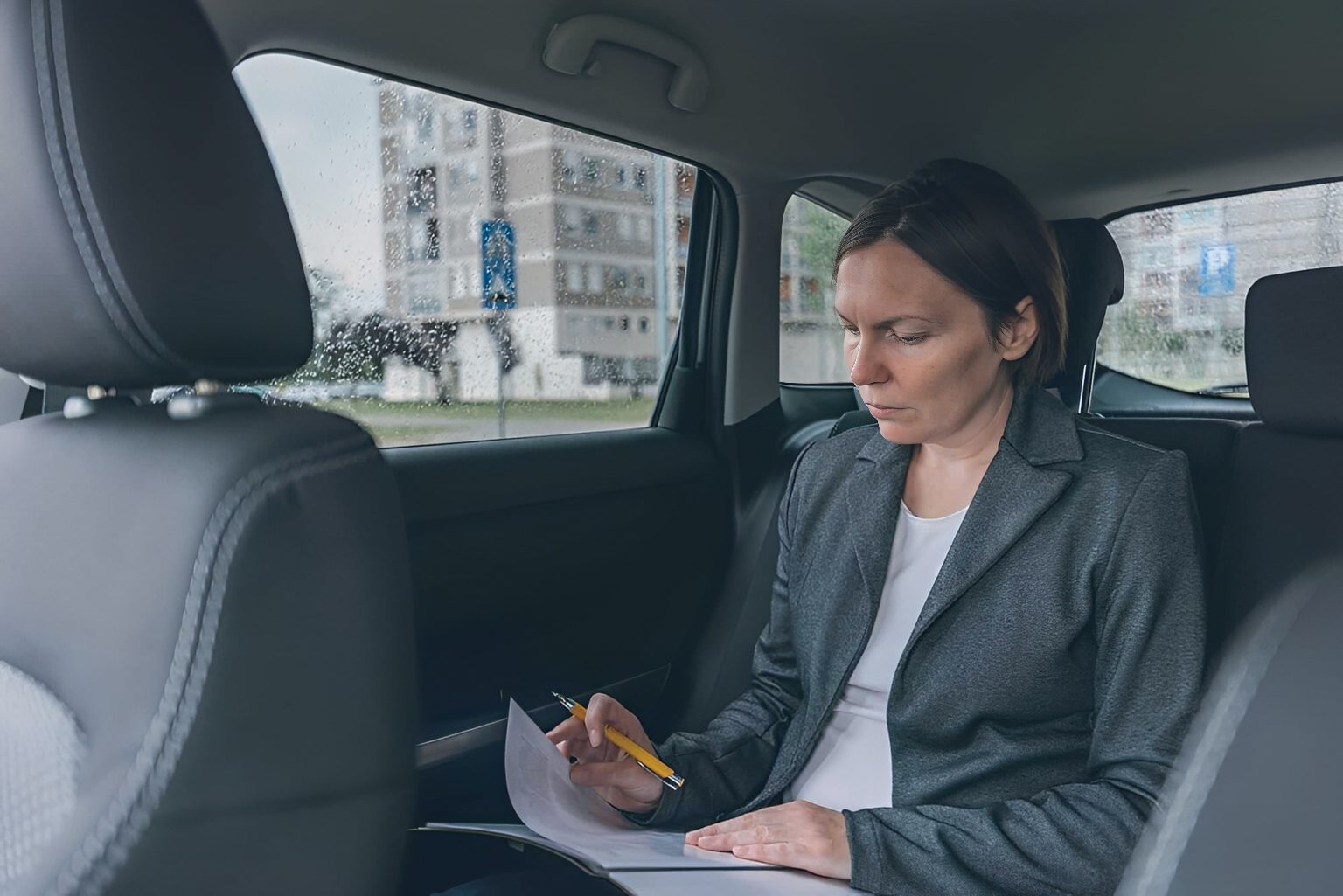 Woman writing in car backseat
